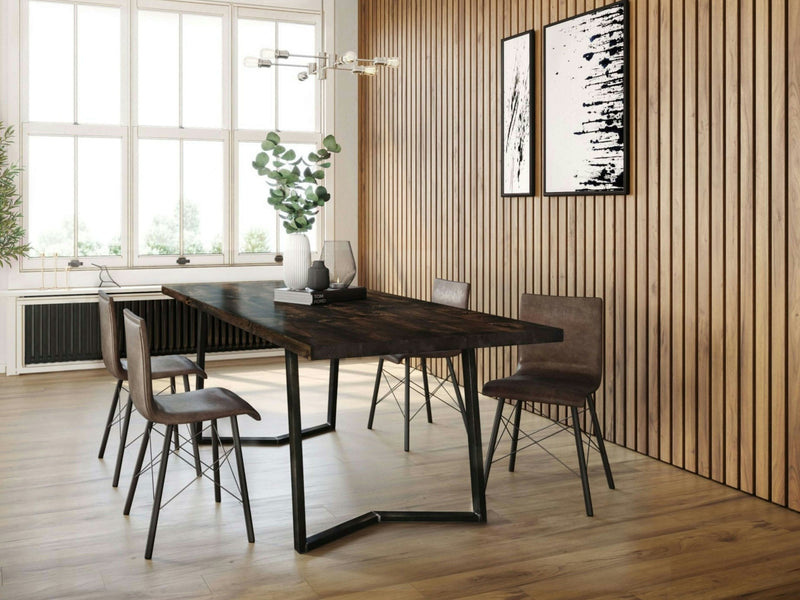 A modern dining room features the Arkwright Dining Table - Tobacco by James+James, surrounded by four brown chairs on a light wood floor. The wall is adorned with vertical wooden slats and two abstract black-and-white paintings. A cluster of green plants in a vase enhances the table's centerpiece, all under contemporary pendant lighting.