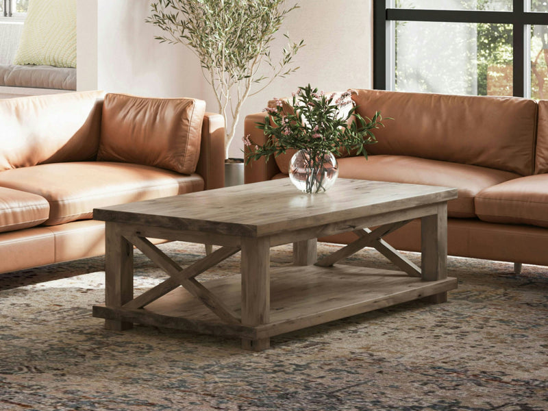 A close-up image of the Carter X Coffee Table - Barn Wood by James+James reveals a natural knot with swirling grain patterns. The knot has a dark center with radiating cracks and irregular shapes, creating an abstract and organic texture against the lighter wood background.