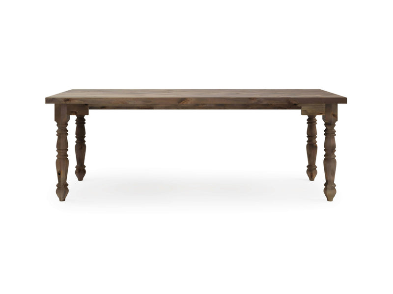 The James+James Turned Leg Desk - Barn Wood is a rectangular wooden table boasting a simple, rustic design. It features a smooth tabletop and four turned legs, each adorned with intricate carved details. The natural finish of the wood adds a warm, classic touch to this piece. The background is plain white.