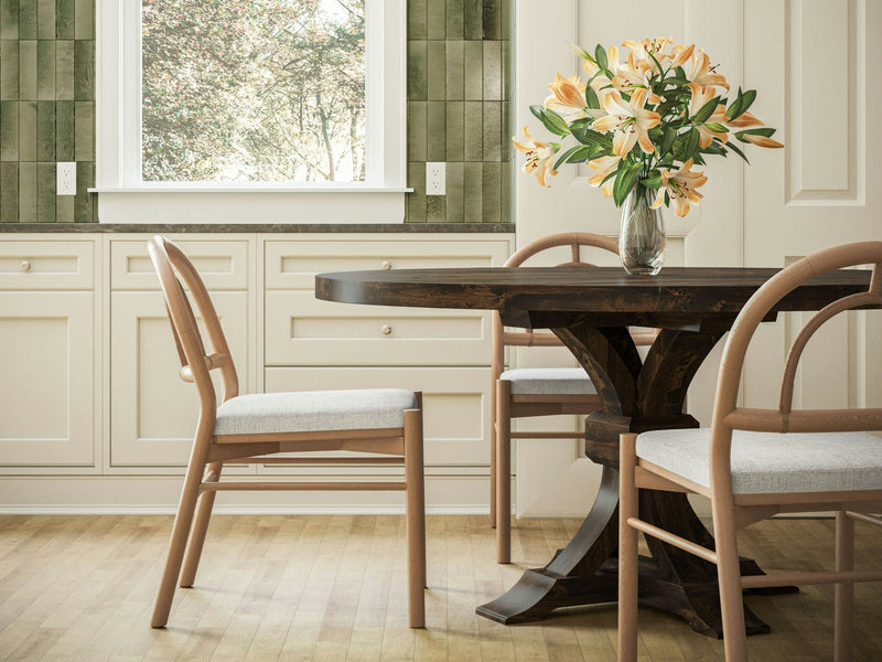 Close-up of the Violet Round Dining Table - Tobacco by James+James, showcasing a dark brown wooden surface with rich, natural grain patterns and textures. The well-polished wood features areas of varying shades, adding depth and visual interest to the material.