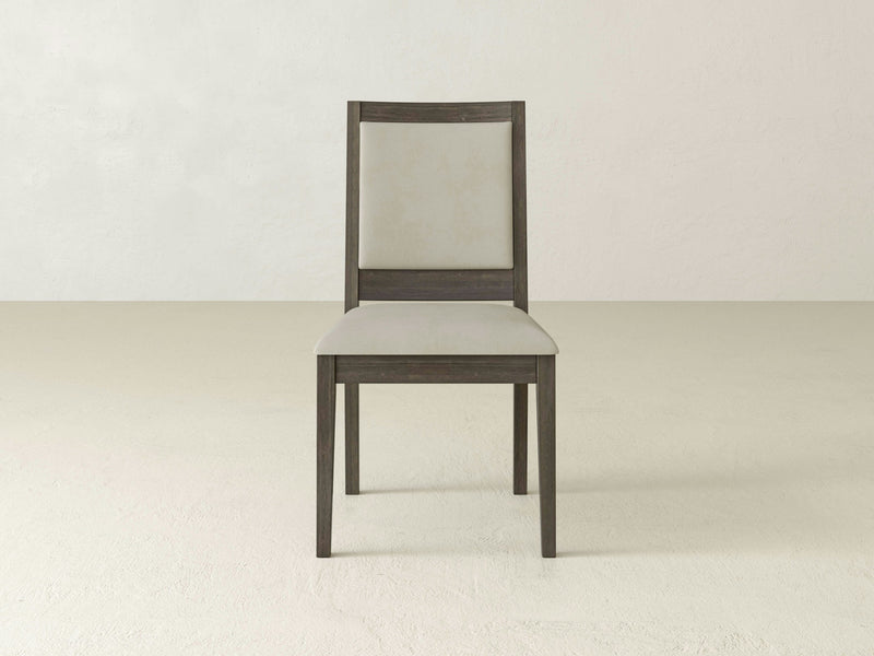 The Gina Side Dining Chair by James+James, crafted from barn wood, features a light gray cushioned seat and backrest. This wooden chair stands against a plain off-white background and showcases straight, dark wooden legs and a simple, minimalistic design.