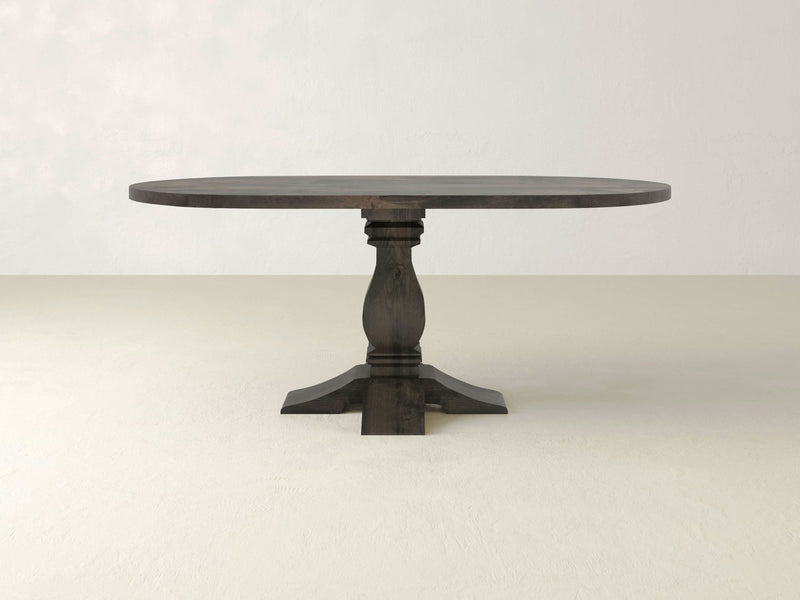 Introducing the Heirloom Oval Dining Table - Deep Grey by James+James. This elegant wooden table features a dark finish and boasts a thick, single baluster pedestal base that branches out into four curved feet for support. With its rustic, sturdy appearance, it adds timeless charm to any dining space.