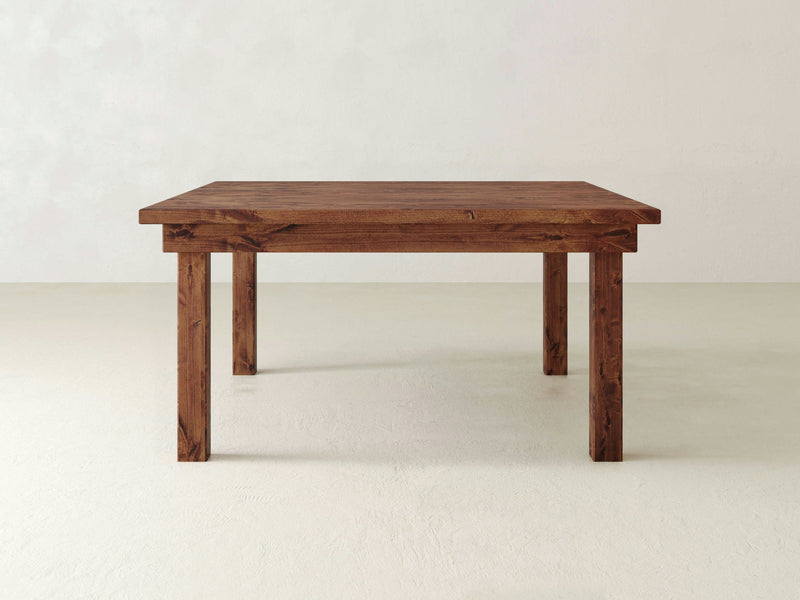 A rustic Farmhouse Square Dining Table - Tuscany by James+James features a simple, rectangular wooden design with straight, sturdy legs. Set against a plain white background, the table showcases its dark, natural finish with visible grain patterns.