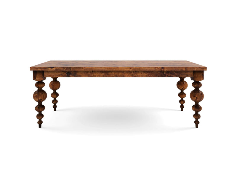 The Olivia Dining Table - Tuscany by James+James is a rustic wooden table featuring a flat rectangular top and four intricately carved spindle legs. Its natural wood finish showcases a rich grain and solid construction, with no objects placed on the table.