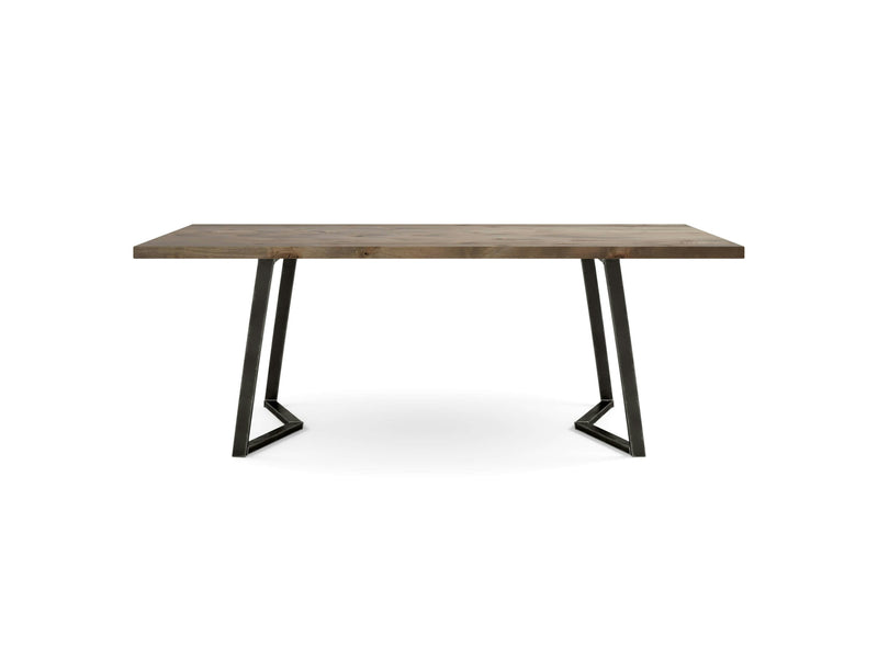 The Arkwright Dining Table - Barn Wood by James+James features a thick, brown wooden tabletop and black metal legs forming angular supports on each side. With its minimalist and modern design, it is suitable for both dining and workspace settings.