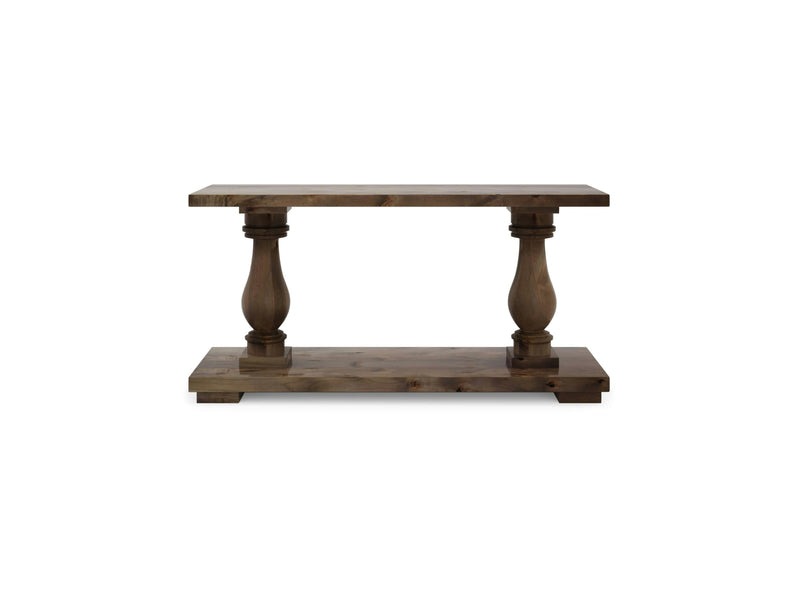 The Vivien Sofa Table by James+James features a rectangular top and base connected by two ornate, carved posts. It boasts a rustic barn wood finish and embodies a sturdy, classic design.