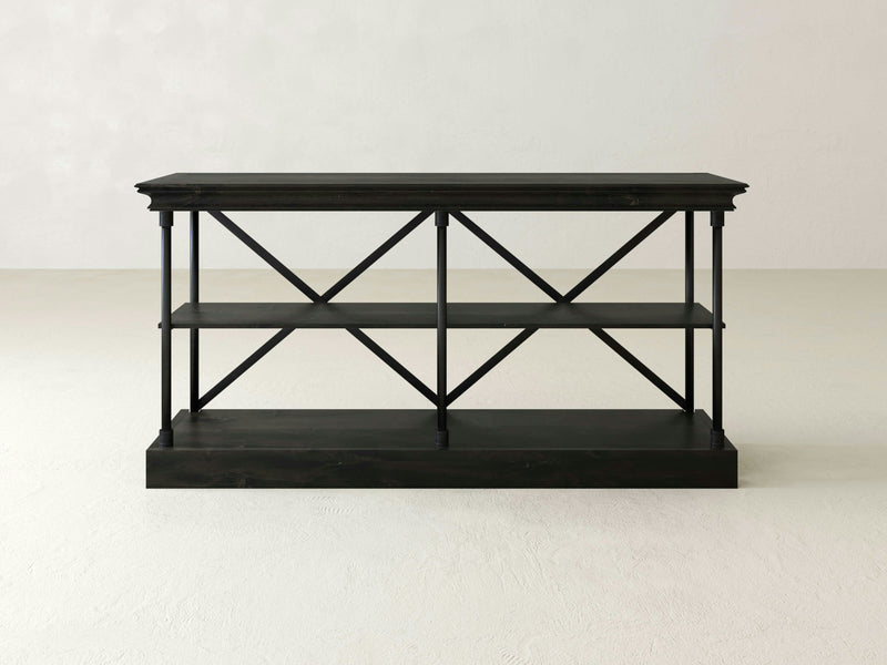 A minimalist dark wooden console table with two shelves, supported by a black metal frame featuring a crisscross design. This James+James Annie Shelf stands on a wide base, its clean and empty background highlighting its simple and modern design.