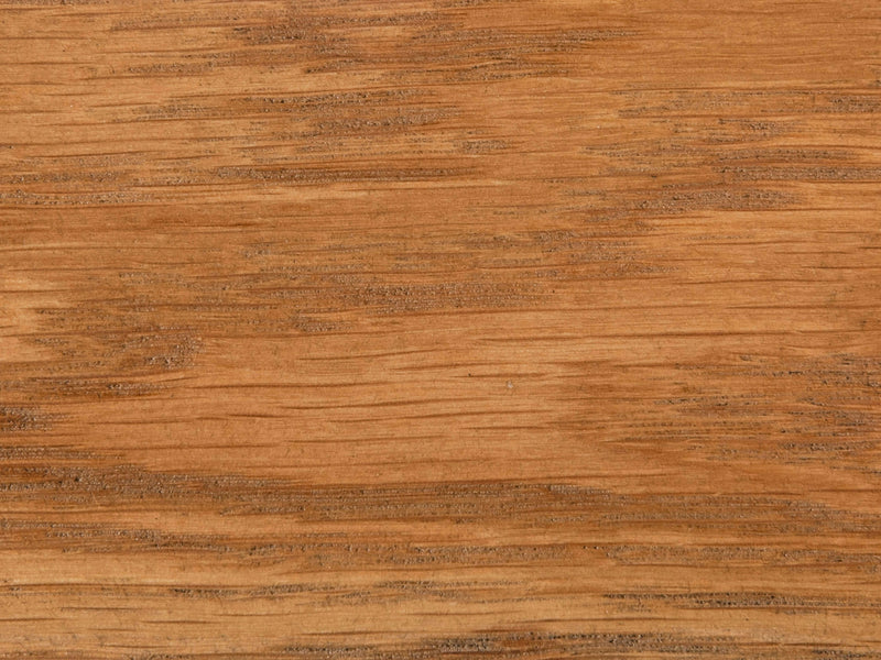 A close-up of the Harvest Wheat on White Oak Sample by James+James reveals a natural grain pattern. The wood exhibits a warm brown hue with varying shades and visible textures running horizontally, creating an organic and rustic aesthetic.