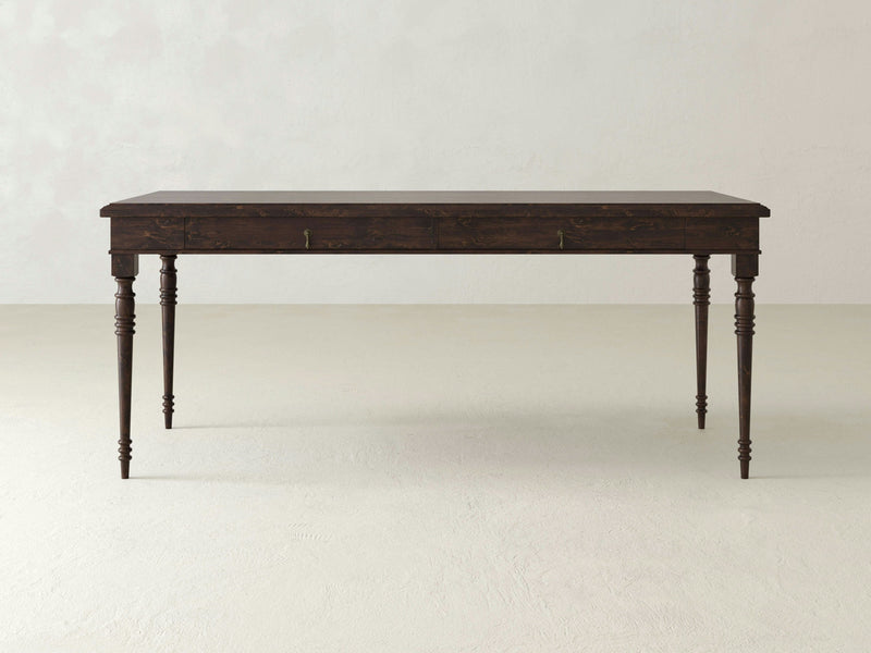 The Audrey Desk - Tobacco by James+James features a close-up of dark brown wood with a coarse, textured grain pattern. Variations in the wood's surface create a mix of lighter and darker areas, giving it a rich, natural look. Small imperfections and lines add character to its rustic appearance.