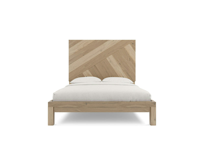 A wooden bed frame from James+James, the Luna - Barn Wood, featuring a large, diagonally slatted headboard. The bed is dressed in white bedding with two pillows, showcasing a simple and minimalist design that highlights its natural wood textures.