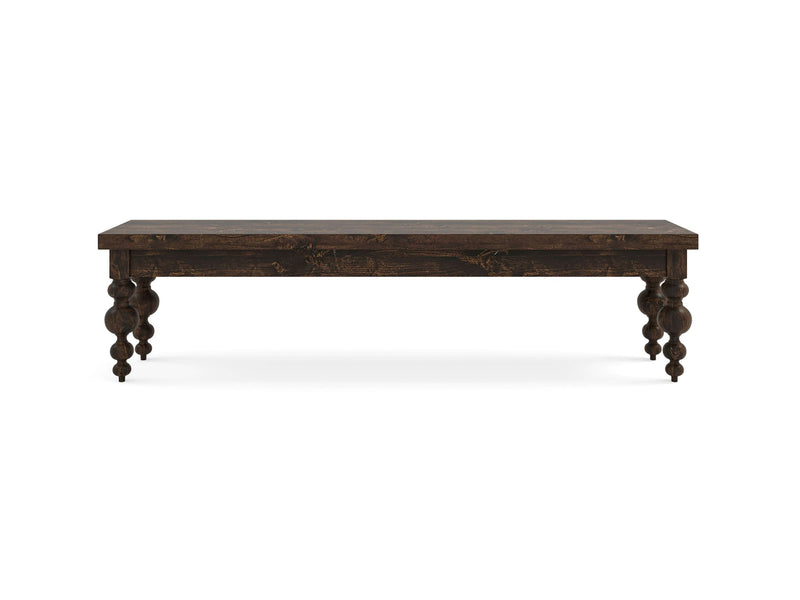 The Olivia Bench - Tobacco by James+James features thick, ornate, turned legs supporting a simple and flat surface with a rich, dark brown finish. This classic and elegant piece showcases intricate leg detailing. The photo of the bench is taken against a white background.