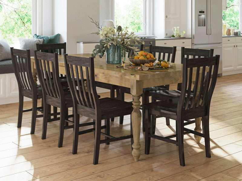 A spacious dining room with the French Country Dining Table - Harvest Wheat by James+James, set for six people. The table is adorned with a centerpiece of white flowers and greenery in glass vases, accompanied by a bowl filled with fruits. The room boasts a modern aesthetic with white cabinets, large windows, and light hardwood floors.