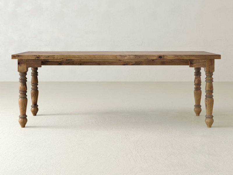 The Turned Leg Desk - Harvest Wheat by James+James boasts a rustic design with a rectangular top and four intricately carved turned legs. The desk features a light brown finish that accentuates the natural wood grain, offering an elegant yet straightforward style suitable for various interior settings.