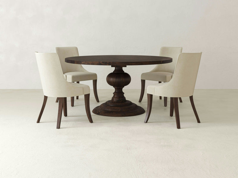 A Josephine & Willow Dining Set by James & James, featuring an upholstered chair with light beige fabric and dark wooden legs, is centered in a minimalist room. In the top right corner, a circular label reads "+ FOUR WILLOW DINING CHAIRS," indicating a set of four handcrafted chairs made in the USA.