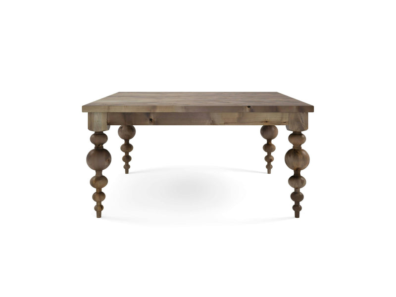 The Olivia Square Dining Table - Barn Wood by James+James is a wooden table with a square top and intricately carved legs, featuring a series of rounded, bead-like segments along each leg. The table boasts a rustic, natural wood finish and is photographed against a plain white background.