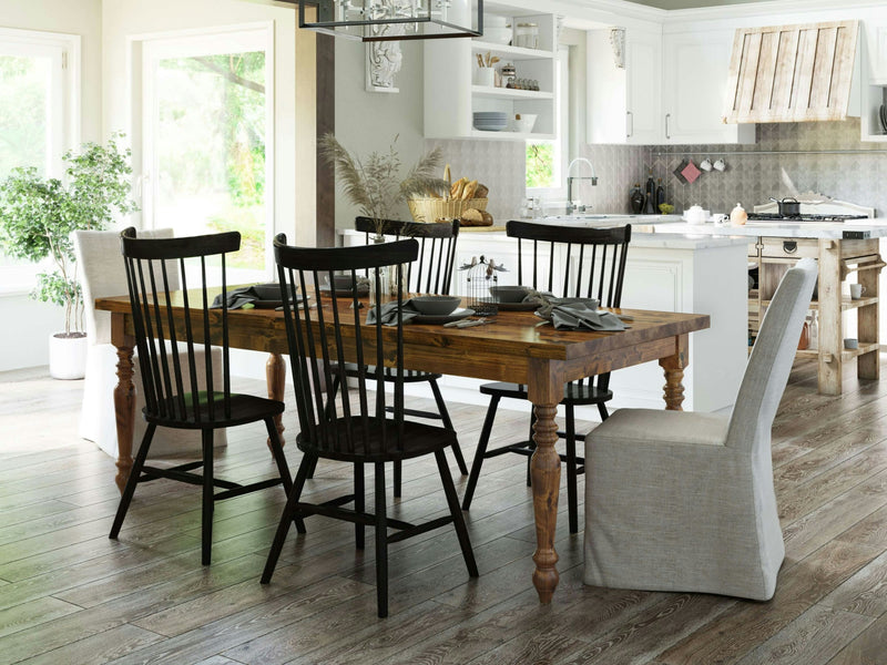 A rustic dining area featuring the French Country Expandable Dining Table - Tuscany from James+James, surrounded by four black spindle-back chairs and two white slipcovered chairs. The table is set for a meal and located adjacent to a bright, modern kitchen with white cabinetry and stainless steel appliances.