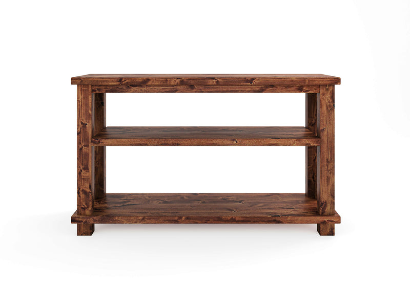 The Carter X Sofa Table - Tuscany by James+James features a rectangular wooden top, two spacious shelves underneath, and a rich, dark brown finish. The table's sturdy, block-like legs complement its simple and functional design, making it ideal for storage or display in a variety of settings.