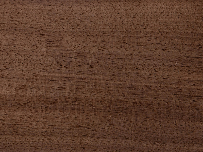 A detailed view of the Barn Wood on Black Walnut Sample by James+James showcases a smooth, rich brown surface. The visible wood grain features a blend of darker and lighter streaks running horizontally, giving it an evenly polished and refined appearance.