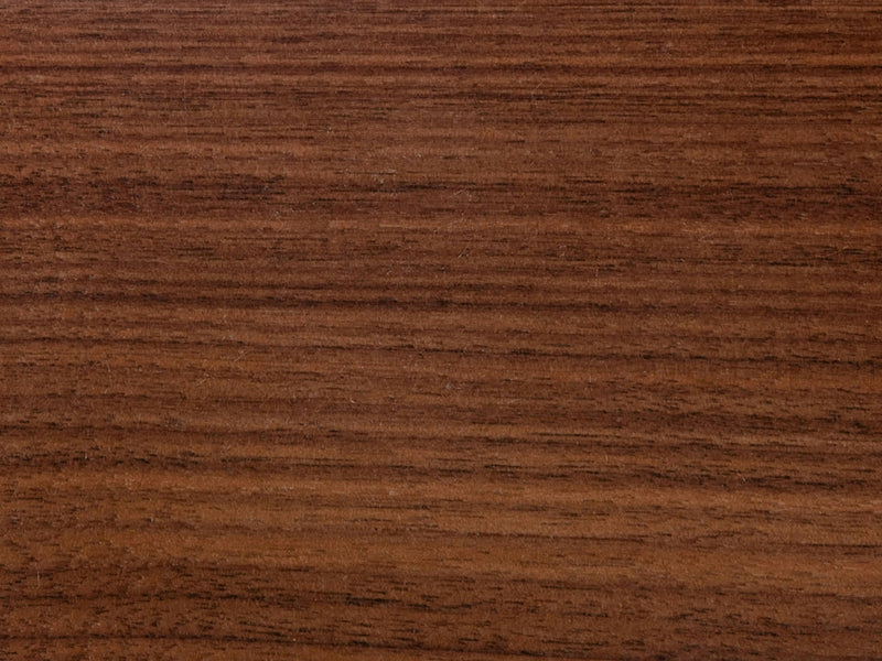 A close-up of the Harvest Wheat on Black Walnut Sample by James+James reveals a smooth wooden surface with a natural, rich brown grain pattern running horizontally. The texture is even and polished, showcasing the wood's natural beauty.