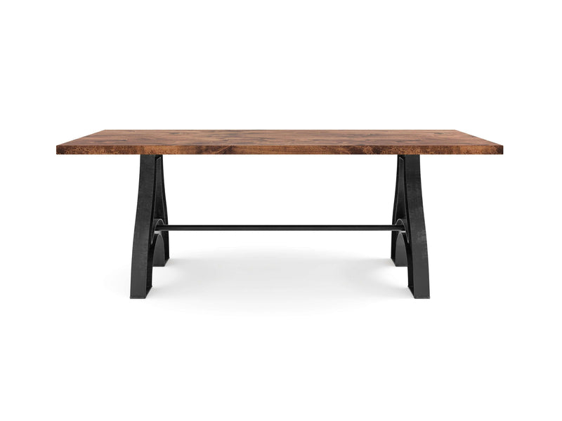 The Wishbone Dining Table - Tuscany by James+James features a rectangular wooden top with a thick, polished finish and sturdy black metal legs. The legs form a trestle base, connected by a horizontal metal bar for added stability. Its simple and modern design makes it suitable for both dining or working.