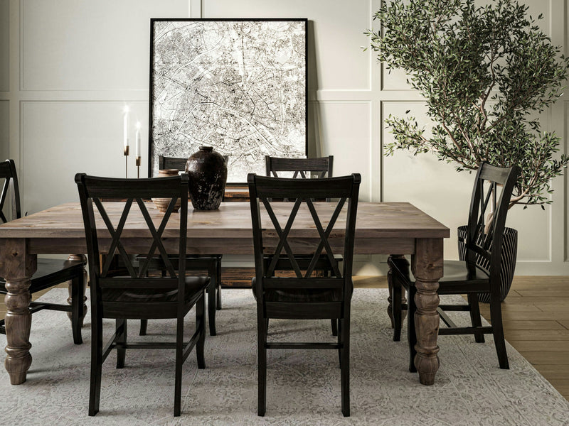 A dining room featuring a James+James Baluster Dining Table in Barn Wood with six chairs. The table is adorned with two tall candles and a dark pitcher. A large abstract painting hangs on the wall behind the table, while to the right, a potted plant adds greenery to the space. The floor is covered with a light-colored rug.