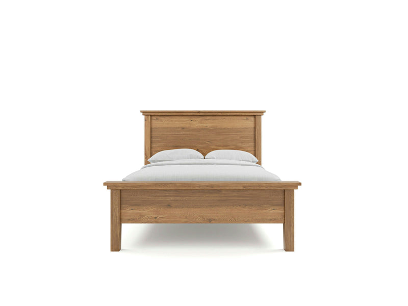 The Ivy Bed - Harvest Wheat from James+James is displayed from the front, featuring a wooden frame with a headboard and footboard. The bed is made up with white pillows and a white blanket, showcasing its simple and classic design that highlights the natural wood grain against a plain white background.