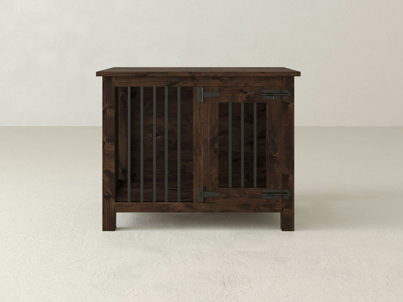 The James+James Single Dog Kennel - Tobacco stands against a light gray background. The front of the wooden pet crate features a door with vertical metal bars and metal hinges, showcasing a simple and functional design.