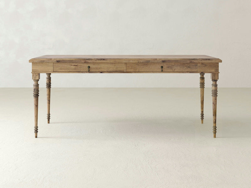 The Audrey Desk - Harvest Wheat by James+James is a rectangular wooden table with four decorative, turned legs. This desk features a natural wood finish and a minimalistic design, exuding a rustic yet elegant appearance.