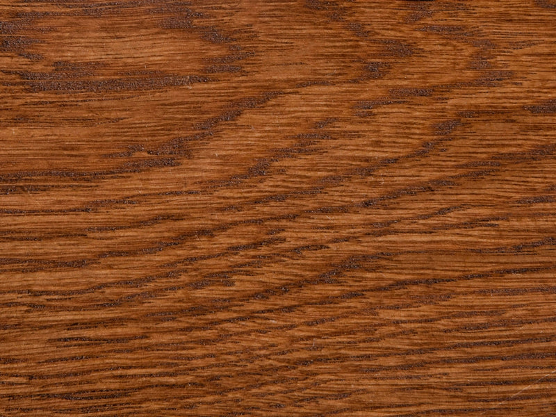 A close-up image of the White Oak Buffet - Tuscany by James+James showcases its rich, medium-brown wooden surface. The wood grain features wavy, natural patterns and subtle variations in tone. The texture appears smooth yet distinct, highlighting the organic and rustic characteristics of the wood.