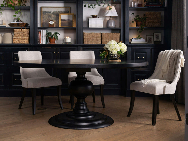 The Josephine Round Dining Table - Charred Ember by James+James features a dark wooden surface with subtle visible grain patterns. The texture showcases varying shades of deep brown and black, enhanced by a slightly curved, lighter brown line running vertically through the center, adding a natural, organic touch to its appearance.