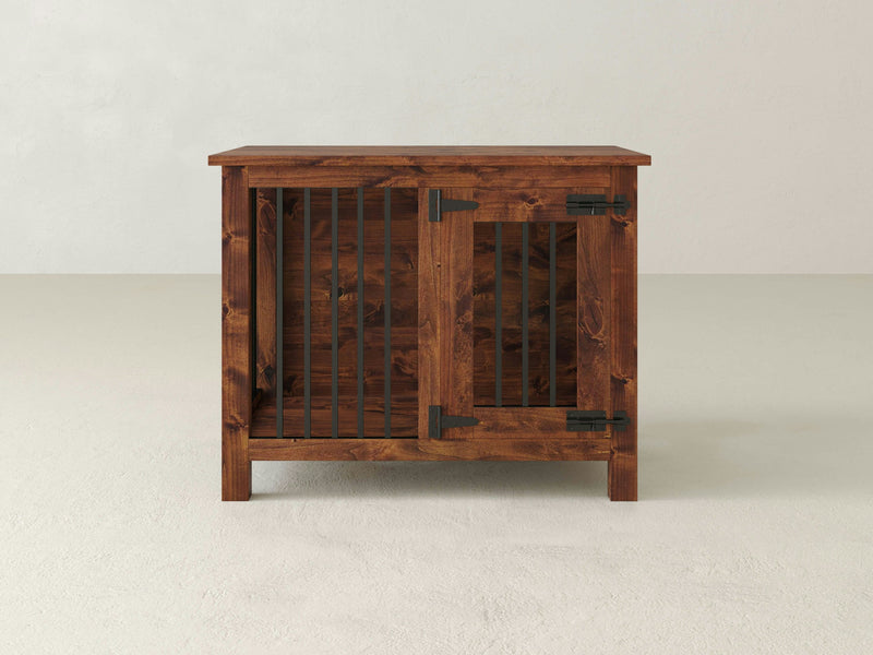 The James+James Single Dog Kennel - Tuscany, crafted from wood and finished in a warm brown color, stands on a light-colored floor against a plain light background. It features metal bars on the front and a hinged door secured with metal latch hardware, embodying a rustic and sturdy design.