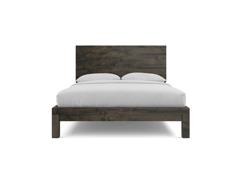 The Sawyer Bed - Deep Grey by James+James boasts a tall, rustic headboard. The bed is adorned with white bedding and two pillows. Its simple, sturdy design features a dark wood finish with clean lines, giving it a contemporary, minimalistic appearance.