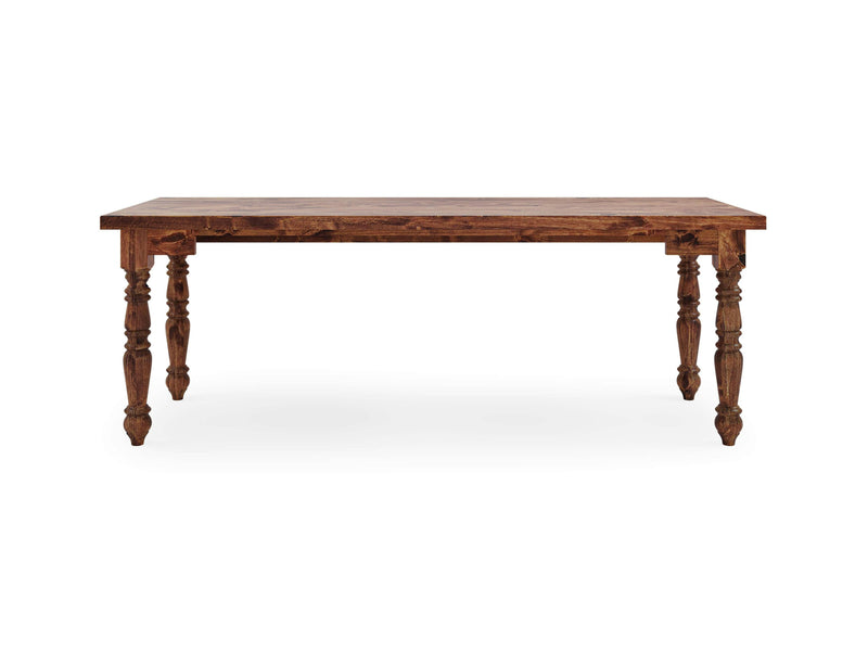 The Turned Leg Desk - Tuscany by James+James features a rectangular wooden tabletop with an elaborate surface design and intricately carved legs. Made from dark, polished wood, the desk stands on four ornate legs, each adorned with detailed carvings. The blank background highlights the desk's exquisite design.