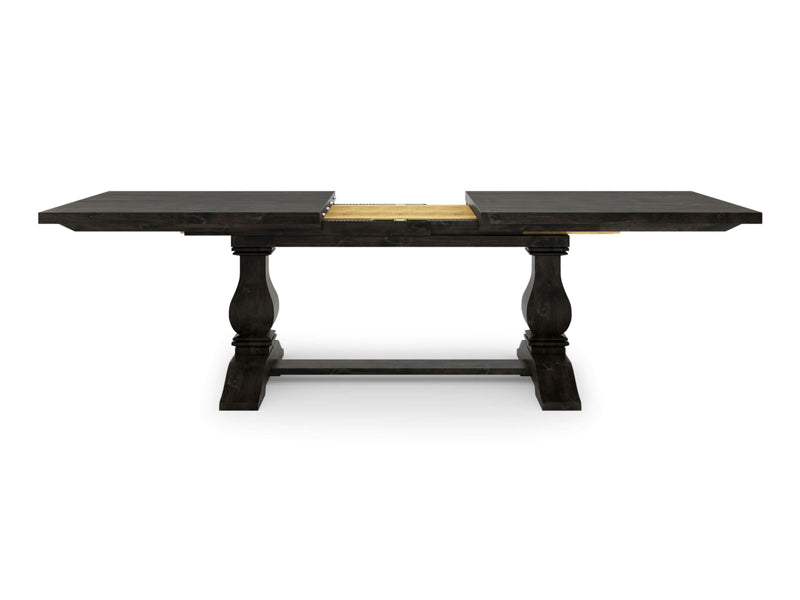 The Heirloom Expandable Dining Table - Charred Ember by James+James features a dark wooden rectangular top with an extendable leaf in a lighter wood color. It stands on two ornate, pedestal-style legs connected by a horizontal support beam, showcasing the elegant and functional design.