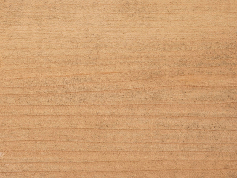 A close-up view of the Harvest Wheat on Maple Sample by James+James showcases a natural, light brown wood surface. The visible wood grain displays a series of horizontal lines and subtle texture variations. While the surface appears smooth, there are slightly worn areas that add character to the piece.