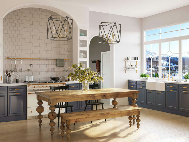 A spacious kitchen boasts a wooden table flanked by the Olivia Bench in Harvest Wheat from James+James, complemented by a vase of flowers. The room features modern lighting fixtures, blue lower cabinets, and white upper cabinets. Large windows flood the space with natural light, offering a stunning mountain view in the background.