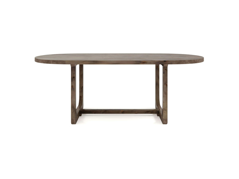 The Emersen Oval Dining Table - Barn Wood by James+James offers a natural wood finish and a clean, minimalist design. Its oval-shaped top is supported by a sturdy wooden base with geometric, rectangular legs.