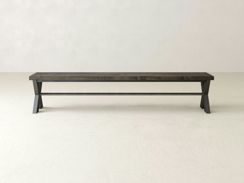 A long, minimalist X-Base Bench - Deep Grey from James+James stands against a white background. The bench features an X-shaped black metal support frame and a rectangular wooden seat, offering a sleek and contemporary design.