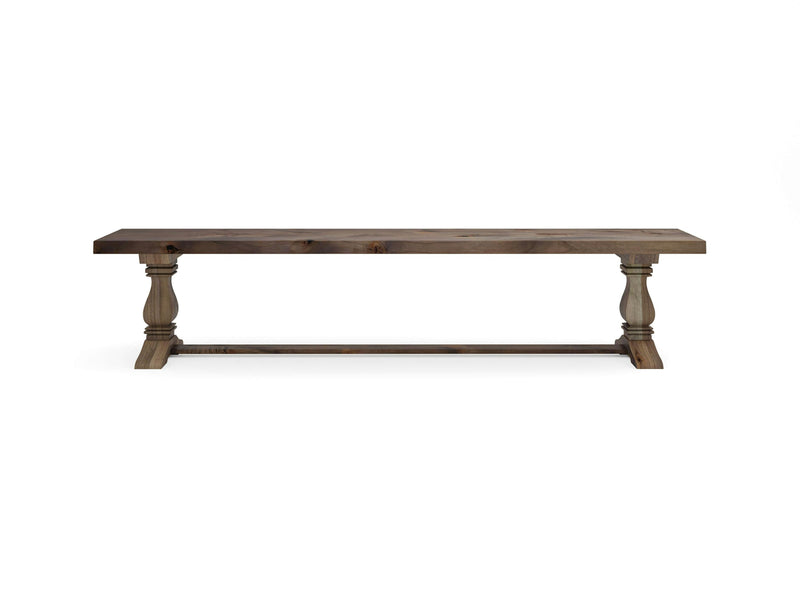 The Heirloom Bench - Barn Wood by James+James features a rustic wooden design with a rectangular seat and two turned legs connected by a horizontal support bar. It boasts a natural, weathered finish that enhances its classic and sturdy appearance. The bench is presented against a plain white background.