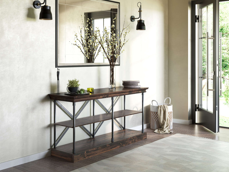 A contemporary entryway features the Annie Shelf by James+James, highlighting handcrafted beauty with metal accents. It holds a large vase of branches and small decor items. Above it hangs a large mirror, while a doorway leads to a lush garden outside.