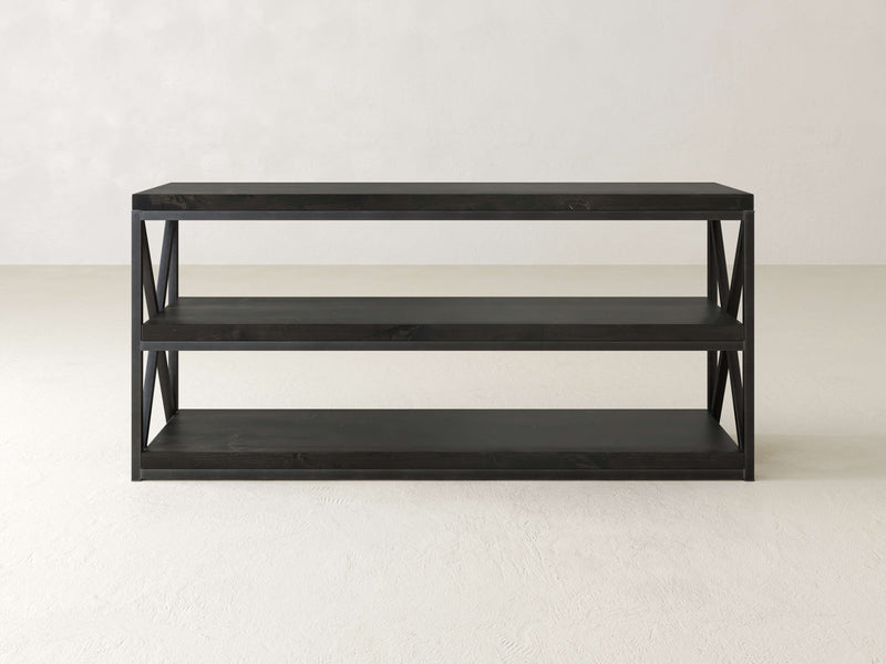 A minimalist black wooden console table with three open shelves and X-shaped side supports, known as the Boyd Shelf by James+James, stands against a plain white background.