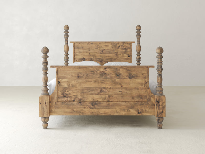 The Catherine Bed - Harvest Wheat by James+James is a rustic wooden bed showcasing a robust headboard and footboard with elegantly turned posts, set against a plain white background. The natural wood features visible knots and grain patterns, adding to its charm.