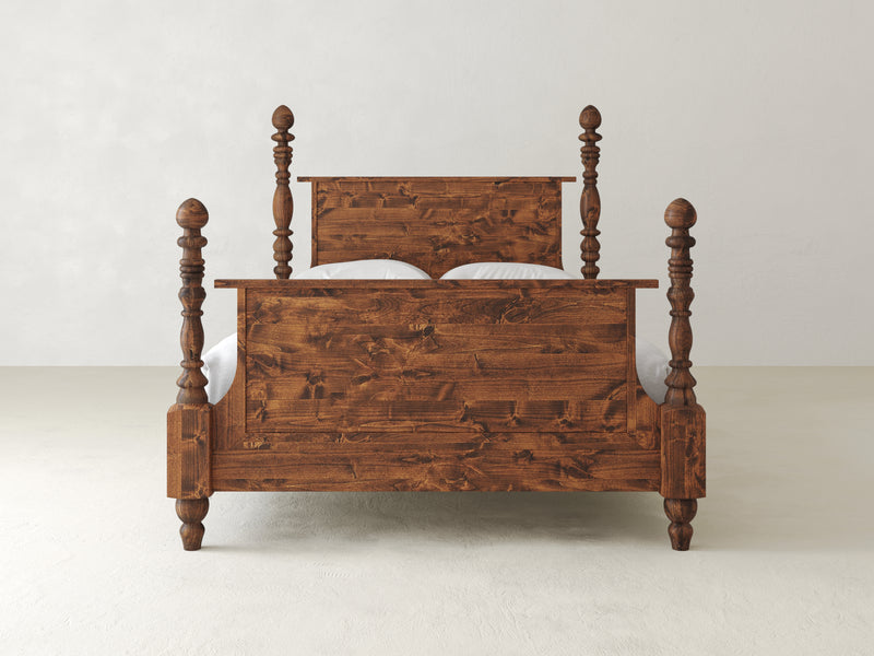 The Catherine Bed - Tuscany by James+James showcases a front view of its wooden design with a high headboard and footboard, adorned with ornate turned posts at each corner. This elegant bed is set against a plain, light-colored wall.