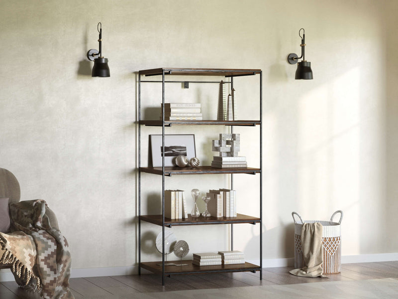 The James+James Gwen Shelf, an artisan-crafted fusion of metal and wood, offers five shelves showcasing neutral-toned decor. It's styled against a light wall with black sconces for an industrial look, complemented by a woven basket and patterned blanket on the hardwood floor.