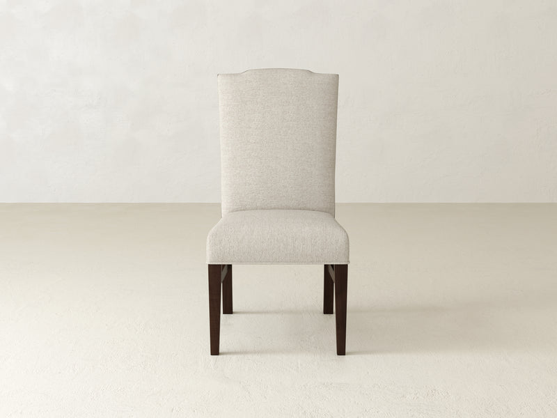 The room features the Hadley Side Dining Chair - Tobacco from James+James, showcasing a high-back design with a textured beige fabric seat and dark wooden legs, set against light-colored walls and flooring.