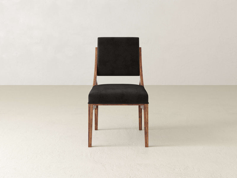 A Quinn Dining Chair - Tuscany by James+James with a sleek, minimalist design stands on a light-colored floor. The chair features a dark padded backrest and seat cushion, offering a simple yet elegant appearance. The background is plain, emphasizing the chair's modern aesthetic.