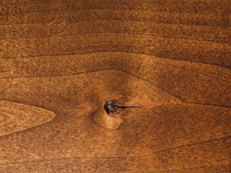 A close-up view of the Nora Buffet - Tuscany by James+James showcases its wooden surface with a prominent knot at the center. The grain and texture are clearly visible, displaying rich, warm brown tones and natural patterns. The knot has a small crack, adding unique character to the wood.