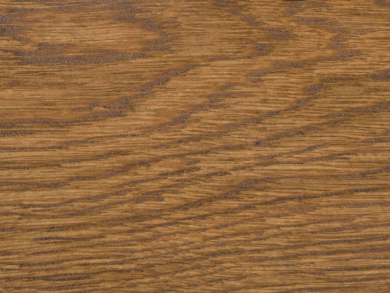 A close-up view of the Tuscany on White Oak Sample by James+James reveals a beautifully warm brown finish. The wood grain stands out prominently, displaying a mixture of straight and wavy lines in an array of brown shades, resulting in a natural and textured pattern.