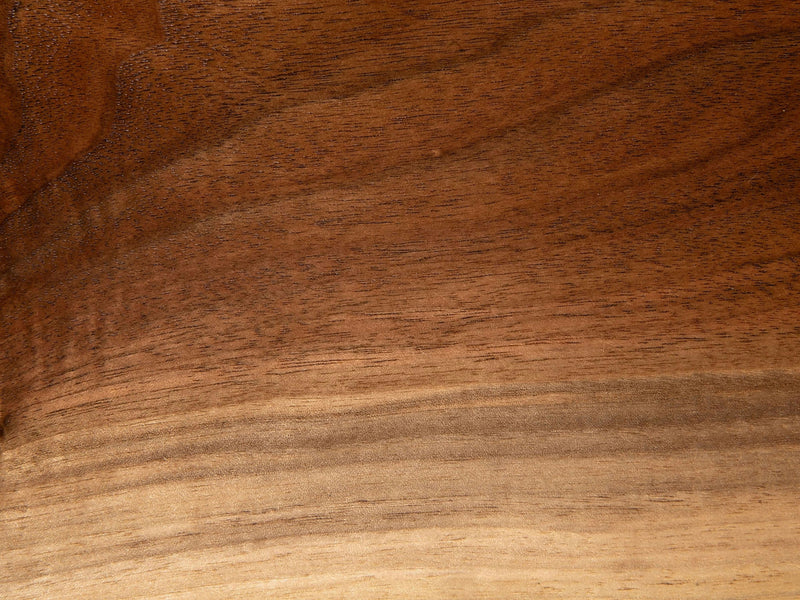 A detailed view of the Satin on Black Walnut Sample from James+James showcasing the natural grain patterns. The wood presents varying shades of brown and beige, with subtle gradients and textures that provide a sense of depth and organic beauty.