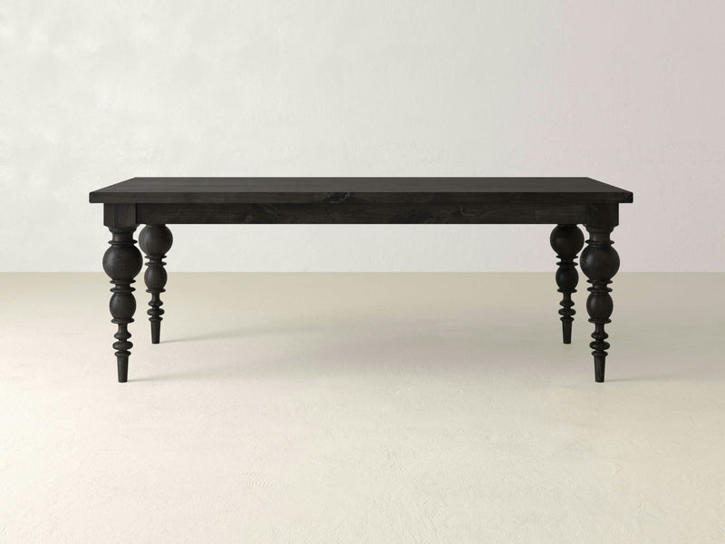 A Bailey Dining Table - Charred Ember by James+James featuring a rectangular top and four ornate, turned legs is placed against a plain, light-colored background. The table showcases a classic, traditional design and appears to be made of solid wood.